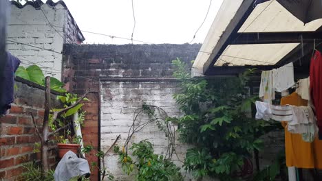 View-of-rain-falling-in-a-small-back-garden-of-a-house,-with-freshly-washed-clothes-hanging-on-wires