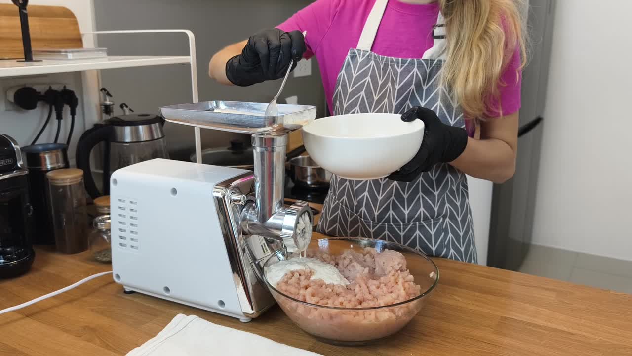 Donna che prepara un composto di pesce macinato per polpette usando un tritacarne