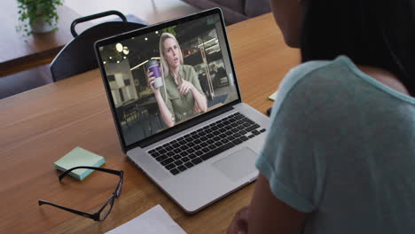 Mid-section-of-african-american-woman-having-a-video-call-with-female-colleague-on-laptop