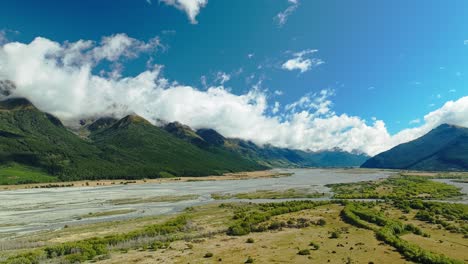 un día vibrante, brillante y alegre por encima de glenorchy, un río alimentado por glaciares, llanuras inundables y montañas.