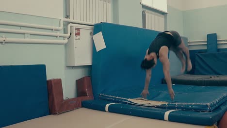 girl athlete practicing fitness at the gym doing back somersault