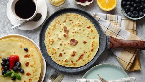 delicious pancakes on stone frying pan  placed on table with various ingredients