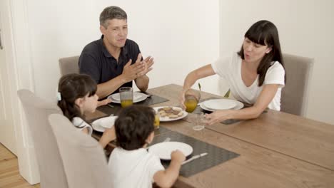 happy family with kids pouring and drinking fresh orange juice