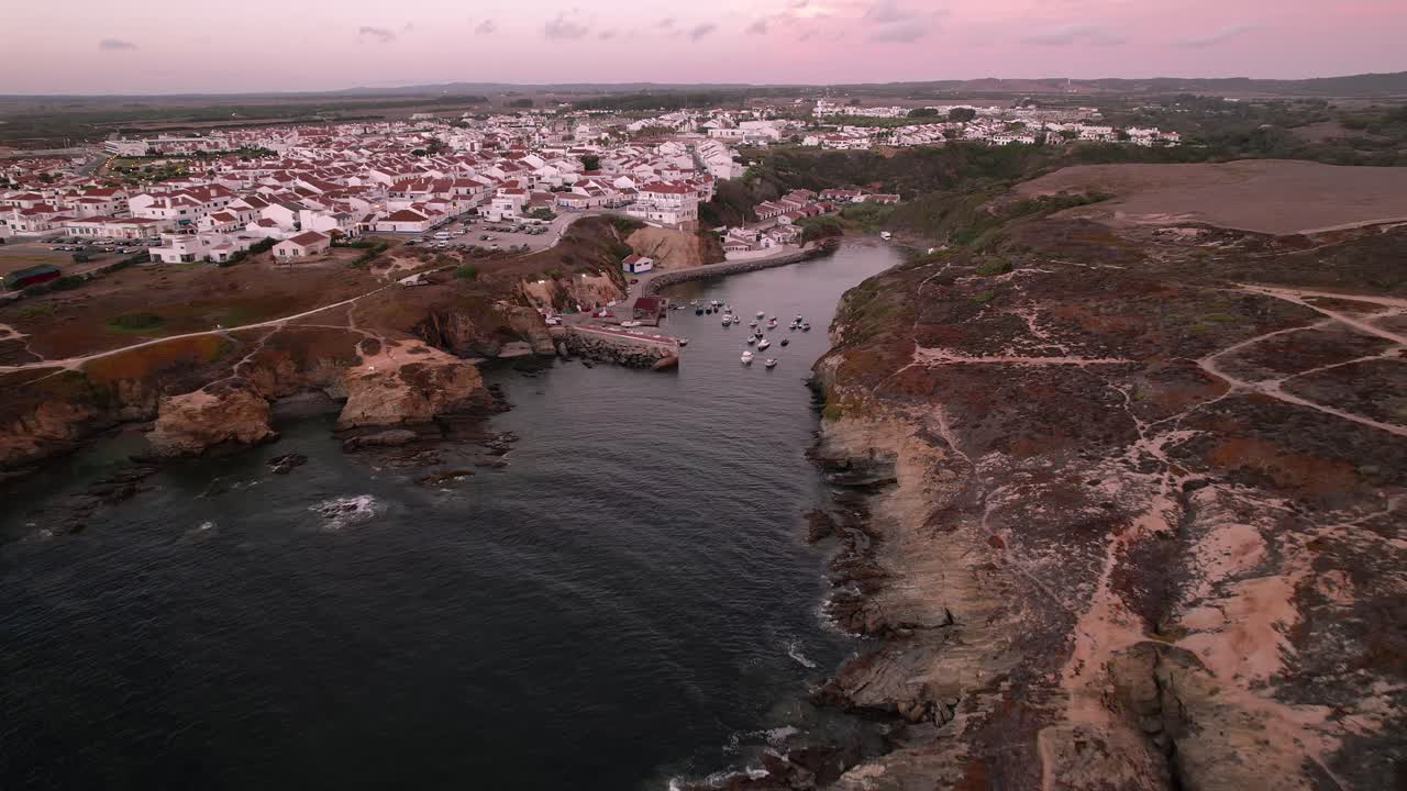 El pueblo de Porto Covo, Portugal, en la región del Alentejo, domina un puerto pesquero esculpido en la escarpada costa atlántica dentro del Parque Natural del Suroeste Alentejano y Costa Vicentina, con impresionantes formaciones de acantilados y casas típicas.