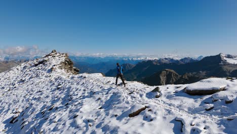 hiker explorer walking and running on snowy ridge mountain with breathtaking views of alps in background, cima fontana, valmalenco in italy