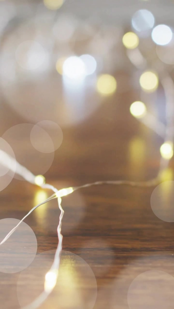 Bokeh lights animation over blurred string lights on wooden surface