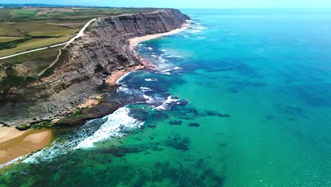 vista aérea del océano, olas aplastantes, playa tropical y acantilados negros empinados, 4k