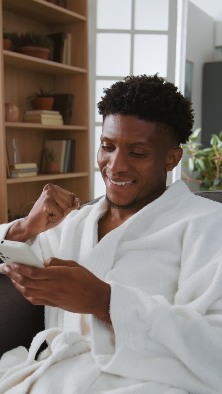 Man in robe using his phone indoors