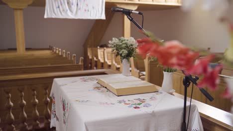 biblia abierta en una mesa pequeña en la iglesia revelada detrás de las flores