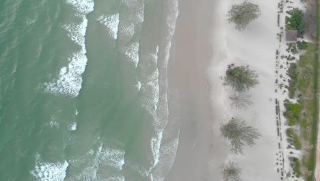 Cinematic-aerial-shot-of-big-waves-crashing-onto-island-coastline-in-cambodia-asia-at-sunset-with-deep-glow-from-sun-over-the-ocean-water-1