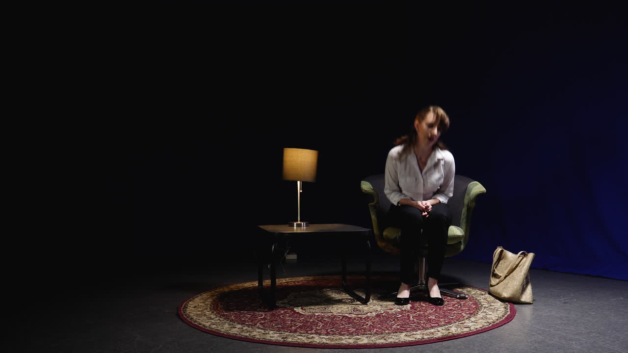 una joven profesional entra en una sala de espera oscura y recibe una llamada telefónica.