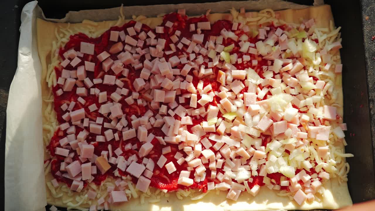 Woman sprinkles onions on homemade pizza in golden hour kitchen lighting