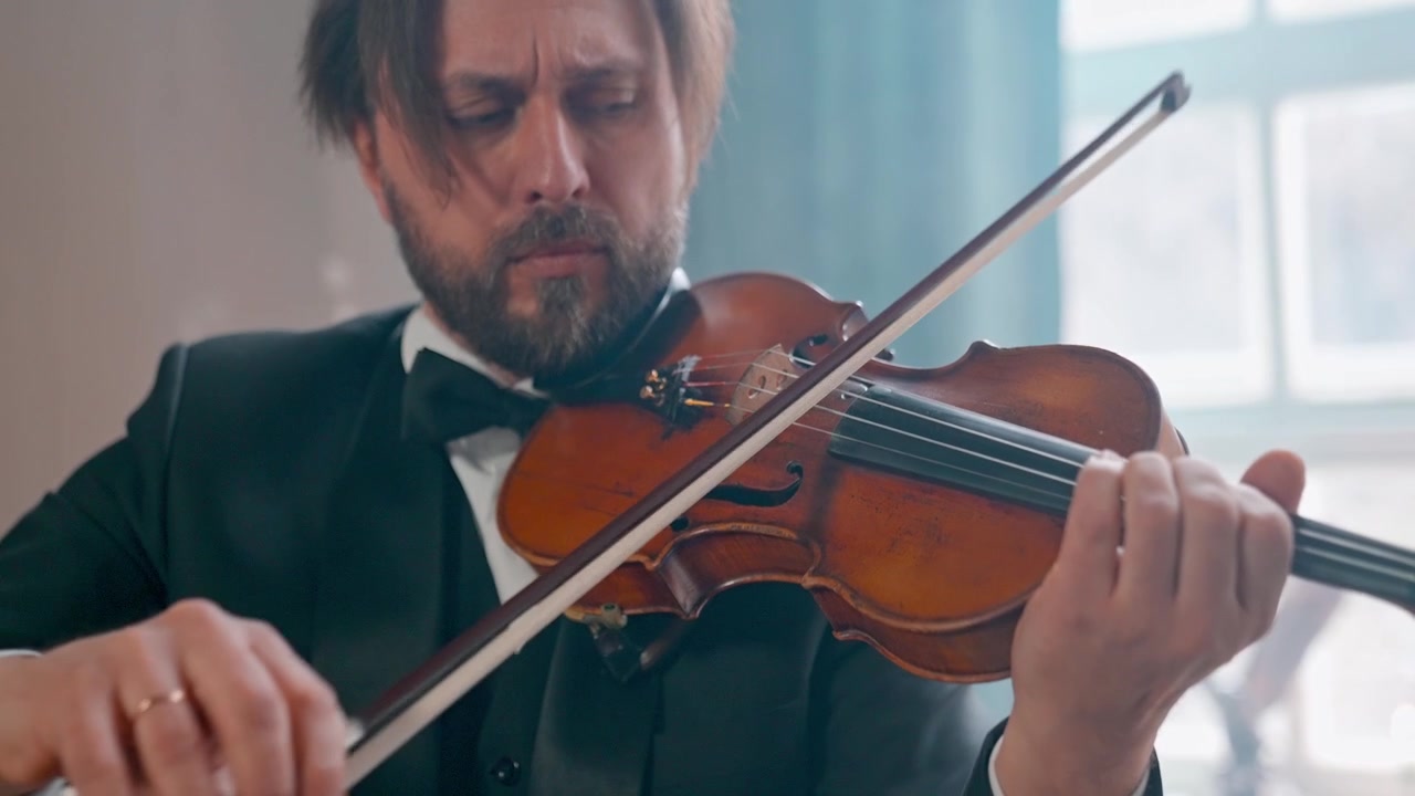 Uomo elegante in smoking che suona il violino con concentrazione