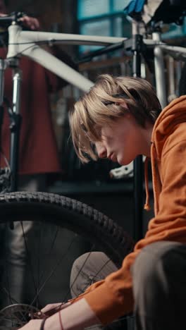 teenager repairing a bicycle in a garage