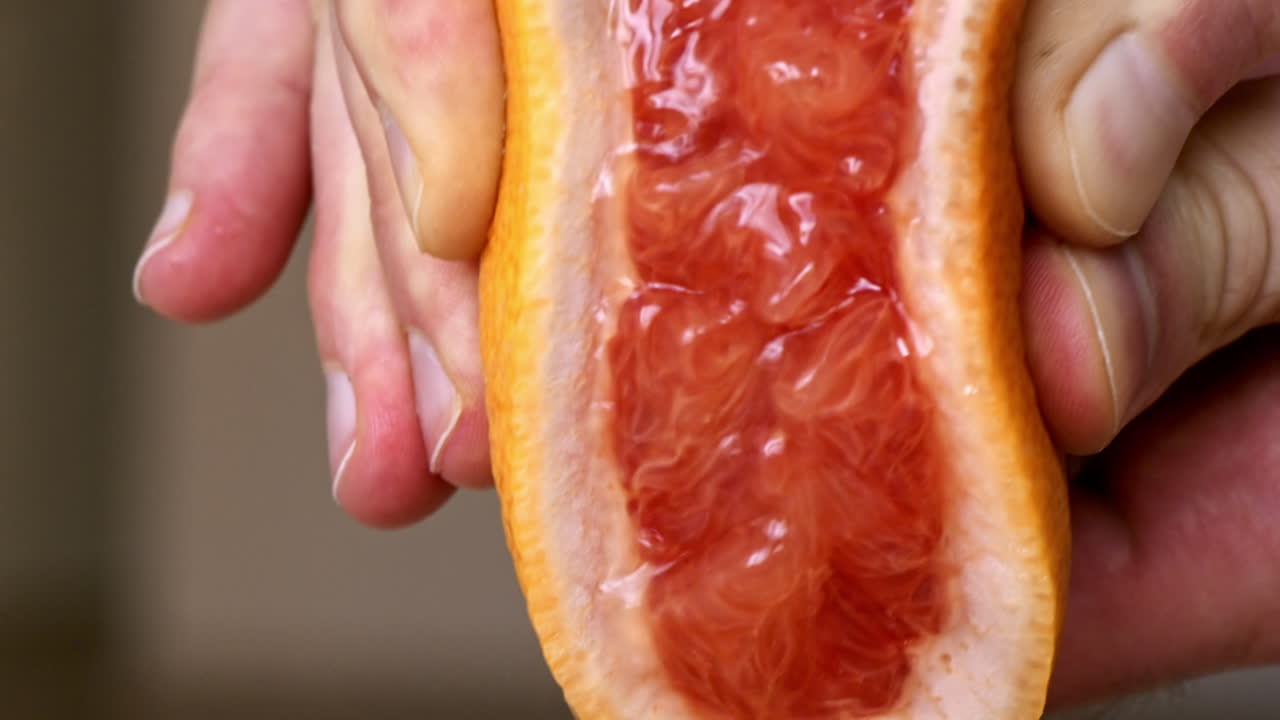 A woman squeezes juice from a grapefruit. Slow motion