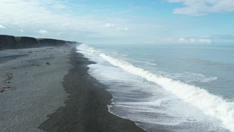 slow-motion aerial view of waves rolling onto stony shore - hakatere beach alluvial cliffs - new zealand