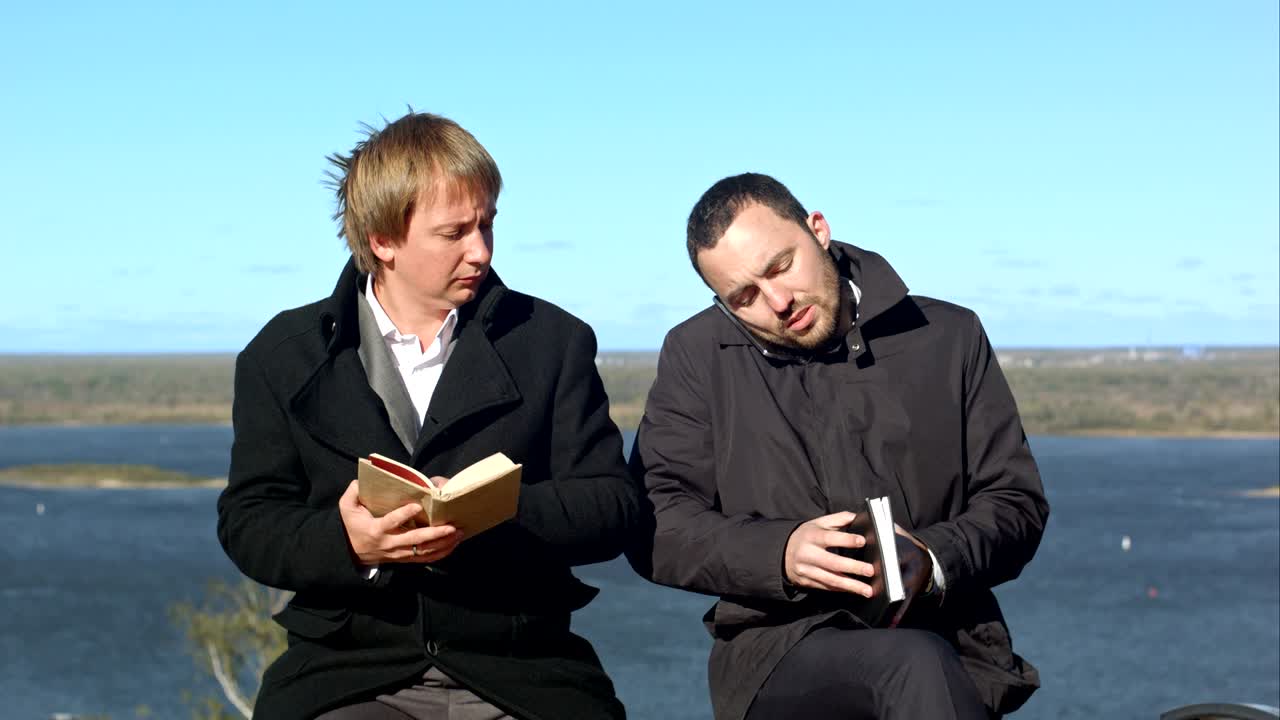 젊은 남자들이 전화로 얘기하고 술에 취한 사업가를 방해합니다.