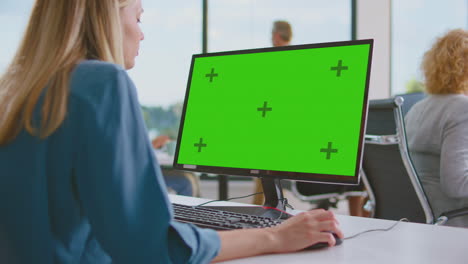 mujer trabajando en computadora en una oficina moderna