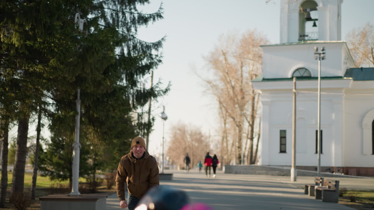 아버지가 보라색 회전 장난감을 공중으로 내보내면서 아들은 떠다니는 장난감에 손을 고, 배경에는 작업 경로를 고 있는 사람들이 있습니다.