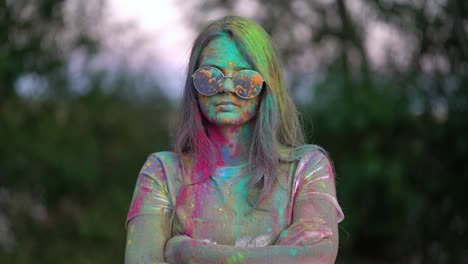 portrait of woman standing being covered in coloured powder at holi festival.