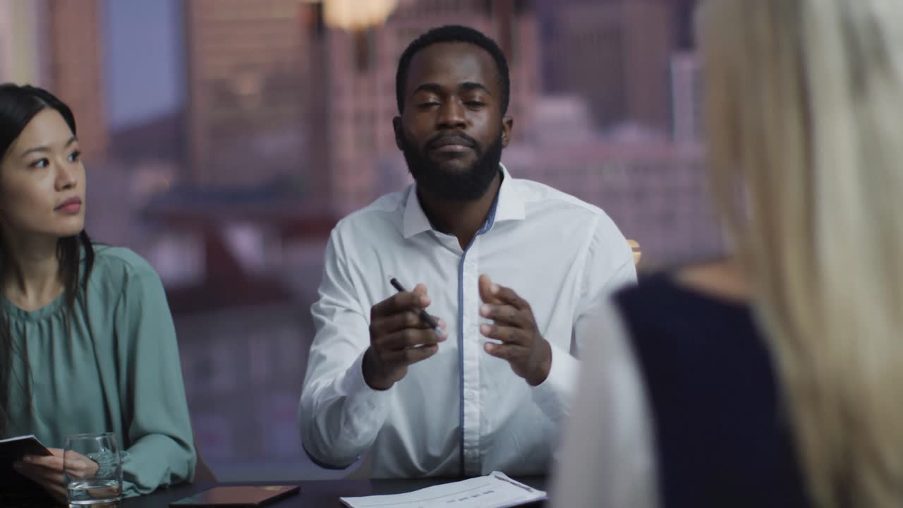 Video of african american businessman talking to diverse colleagues at evening office meeting