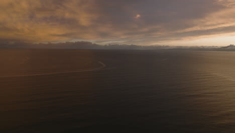 lone fishing vessel sailing across the calm waters of tasman bay in new zealand during the early hours of sunrise.