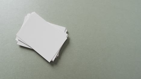 Overhead-view-of-stack-of-blank-white-business-cards-on-grey-background,-copy-space,-slow-motion