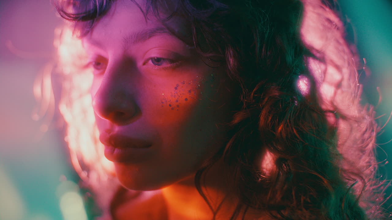 Portrait of Young Attractive Woman with Glitter on Cheek in Neon Light