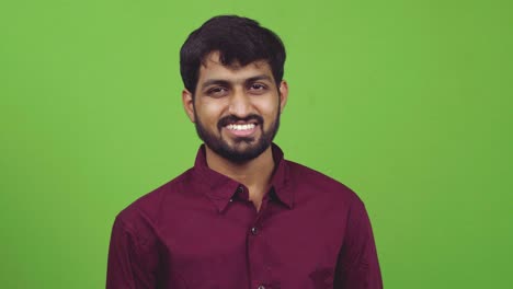 attractive indian man looking towards camera and smiling, isolated on green screen