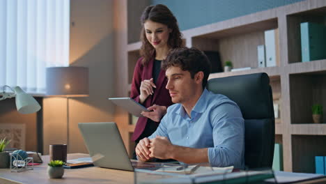 businessman video calling laptop working in office with woman assistant close up