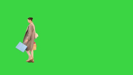 young attractive woman in a coat walking and making a spin on a green screen, chroma key