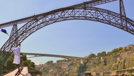 old maria pia bridge seen from tourist boat spanning two old town in porto, portugal at daytime