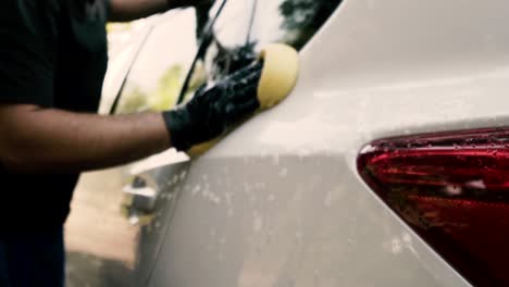 Primer-Plano-De-Un-Hombre-Lavando-Un-Auto-Usando-Guantes-Negros-Con-Champú-Y-Esponja