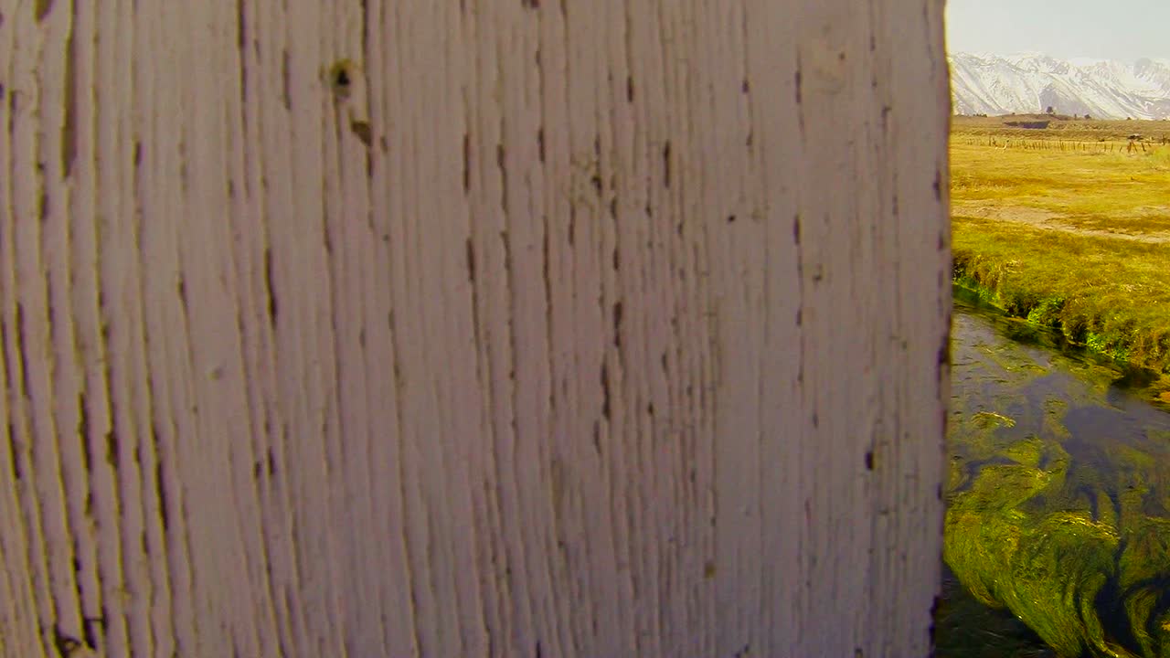 카메라가 다리를 가로질러 이동하여 아름다운 시에라 강과 산 배경을 드러냅니다.