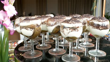 Vasos-Elegantes-Con-Un-Colorido-Postre-Tiramisú-Dispuestos-Sobre-Una-Mesa