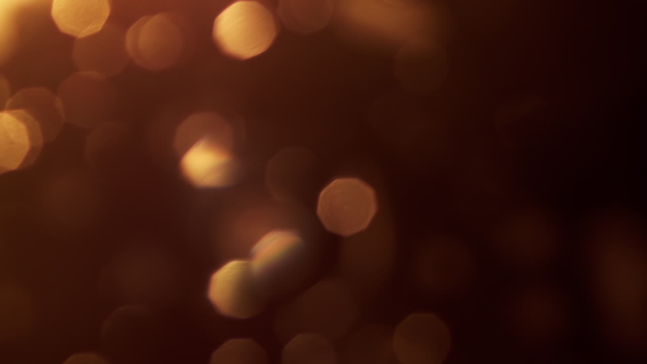 Luci bokeh dorate calde e scintillanti su sfondo scuro