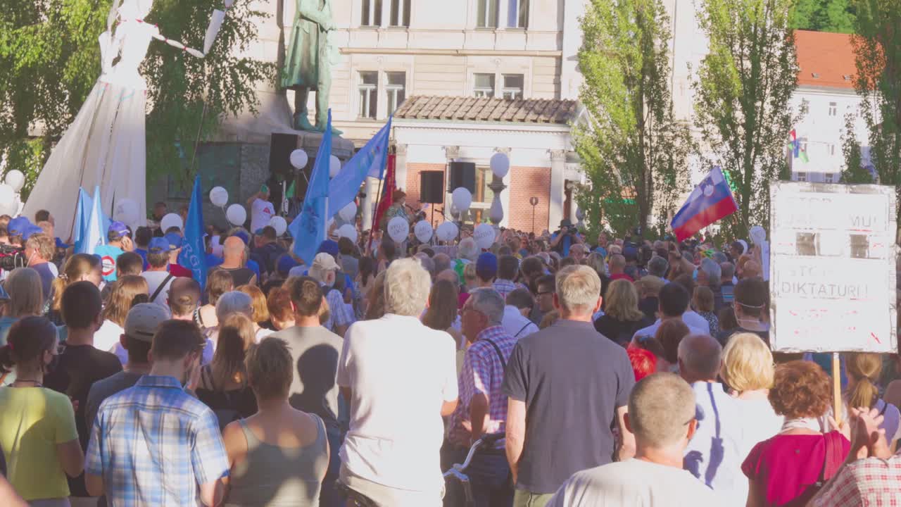 Hundreds Of People With Slovenian Flags, Banners, And Balloons Out In The Street To Demonstrate Against Government During Statehood Day In Ljubljana, Slovenia. medium shot