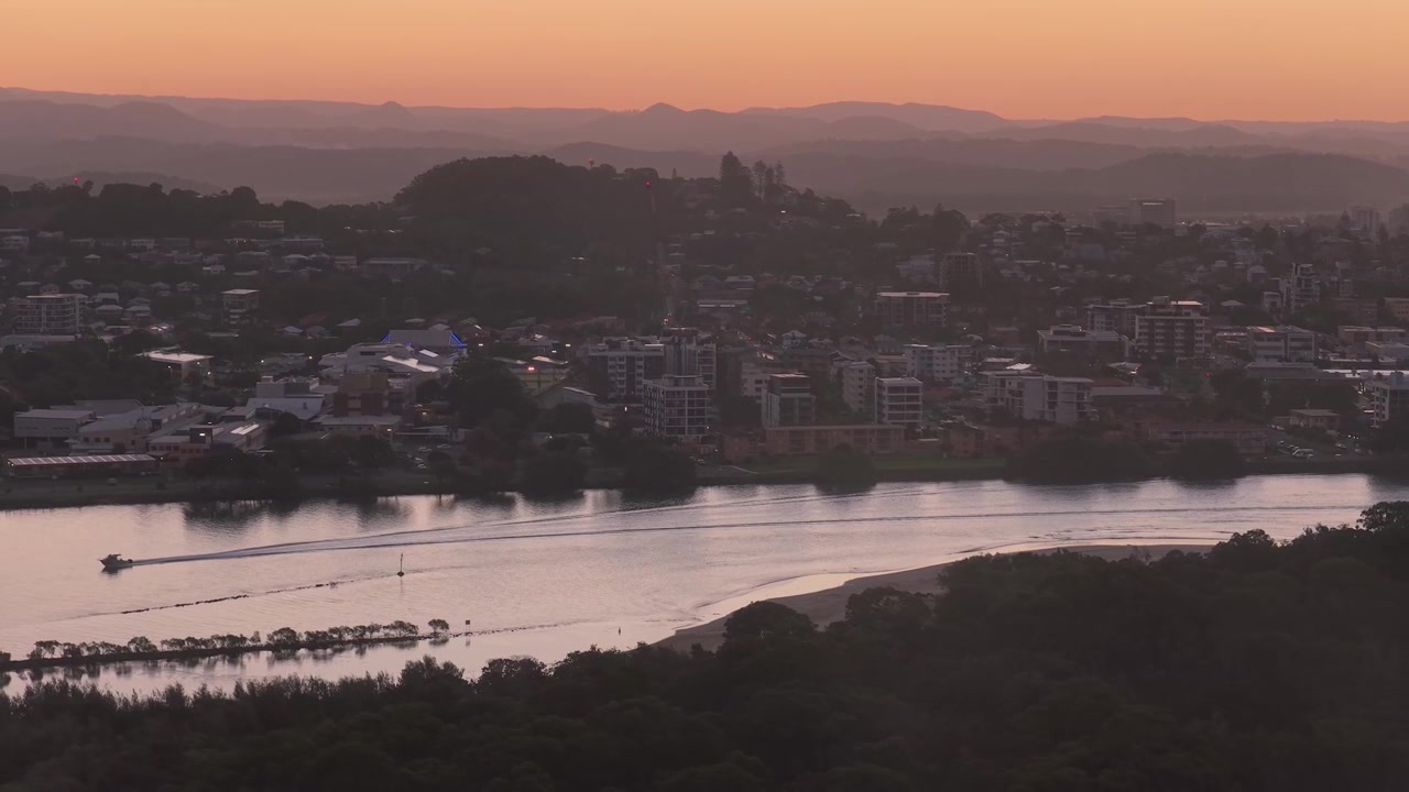 Motoscafo che naviga attraverso il Terranora Creek al tramonto nel Nuovo Galles del Sud, Australia. - Ripresa aerea laterale.