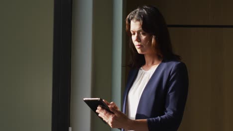 portrait of caucasian businesswoman with brown hair using tablet in modern office