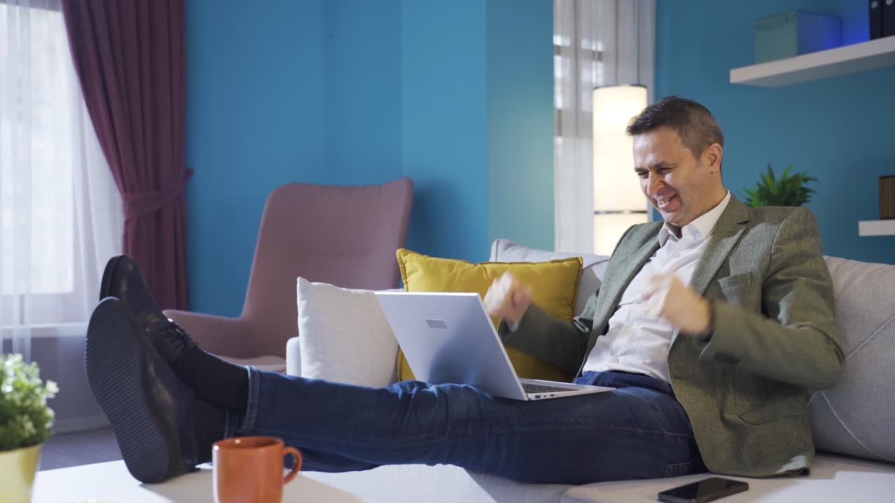 hombre de negocios maduro acostado en el sofá en casa regocijándose en su éxito, alegre.