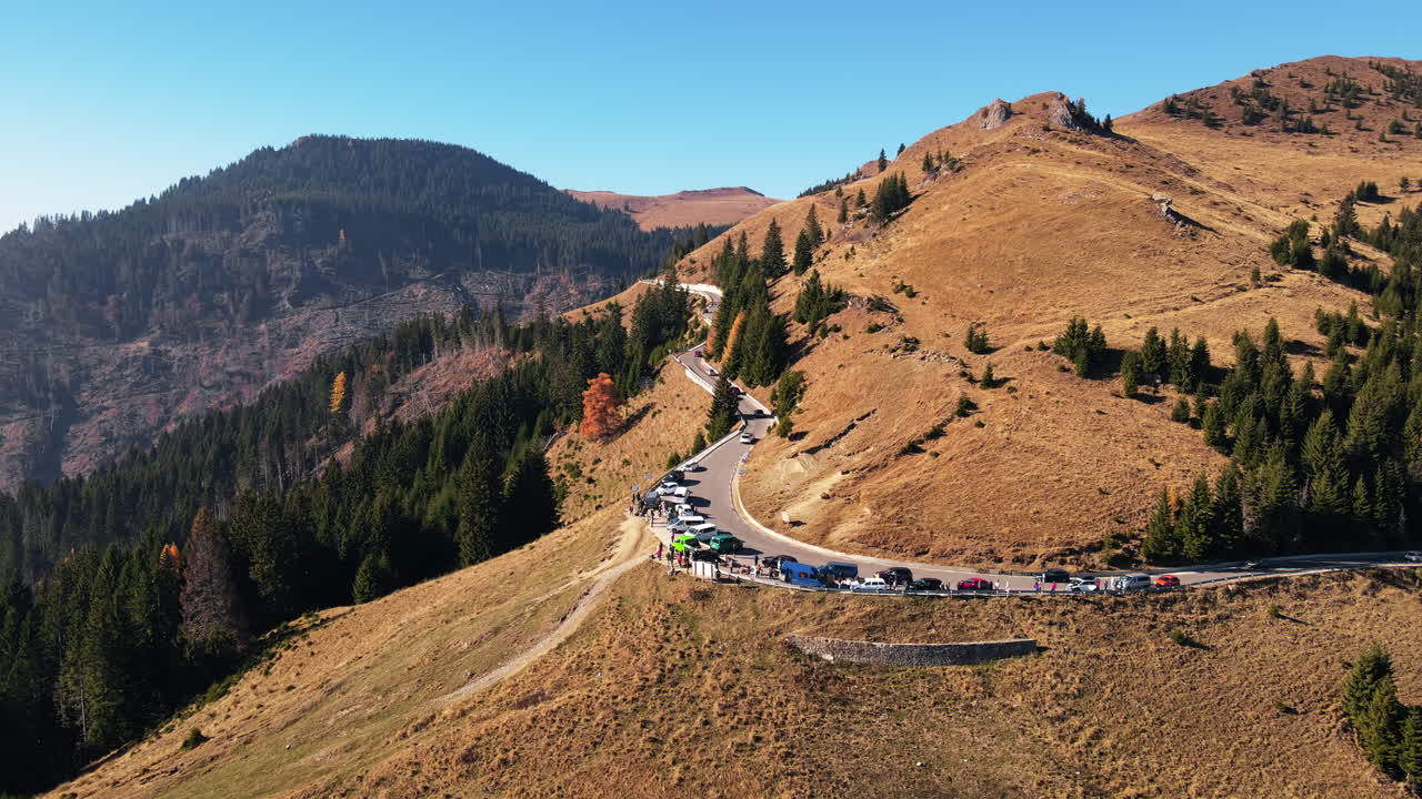 Aerial drone view of a road in Bucegi Mountains in Romania. Parked and moving cars, green firs