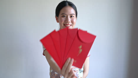 belle femme asiatique porte une robe traditionnelle chinoise avec une enveloppe rouge ou un paquet rouge