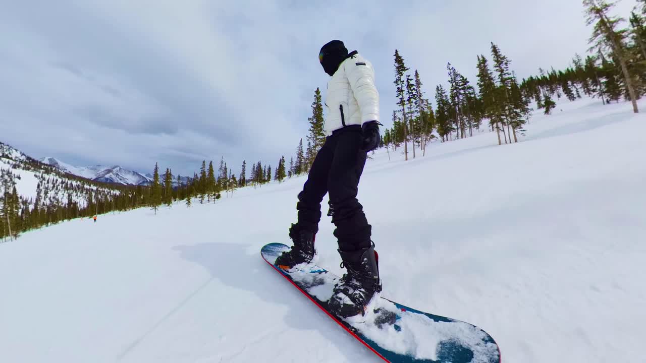 persona haciendo snowboard en invierno por una montaña en colorado