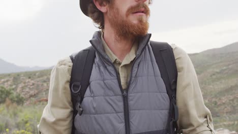 Bearded-caucasian-male-survivalist-on-mountain-in-wilderness-holding-map-and-looking-around