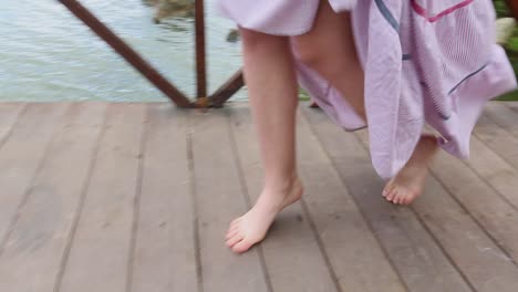 woman walking barefoot on a wooden bridge over water