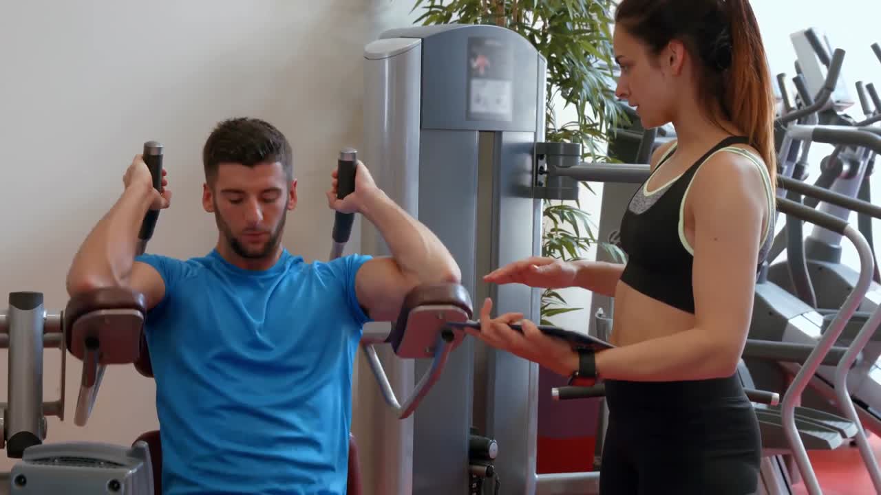 pareja usando una máquina de pesas en el gimnasio