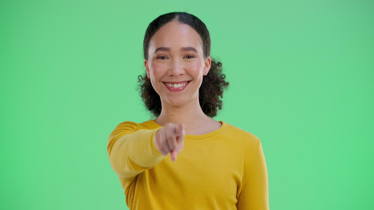 Smilende kvinde peger på kameraet på greenscreen
