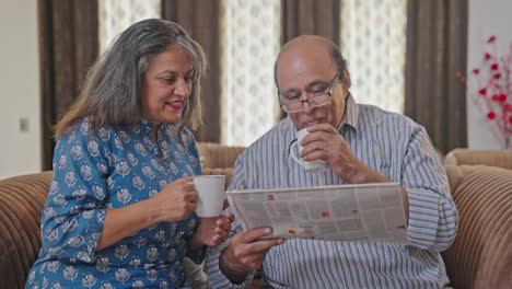 Indische-Frau-Bringt-Ihrem-Mann-Tee,-Während-Er-Zeitung-Liest