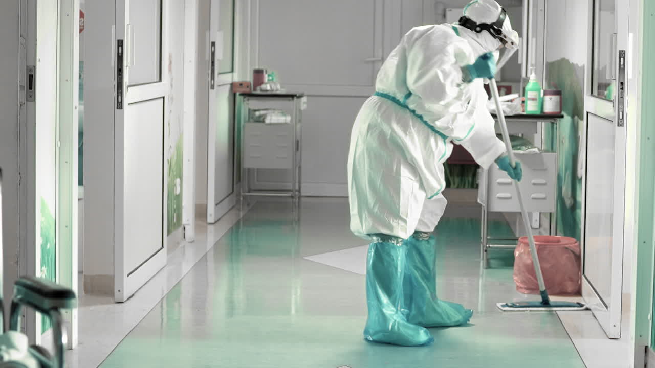 limpieza del piso del hospital con ropa protectora completa, condiciones de trabajo difíciles durante una epidemia