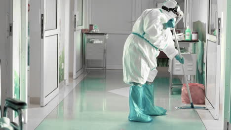 limpieza del piso del hospital con ropa protectora completa, condiciones de trabajo difíciles durante una epidemia